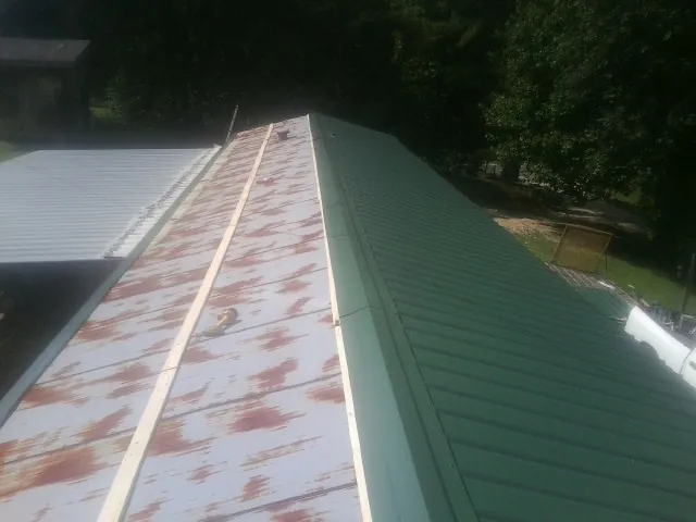 Old rusted panels beside newly installed green metal roofing — Wind Damage Roof Repair by Roofing Brothers in Rocky Ridge