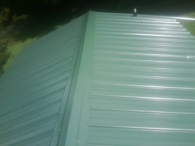 New green metal panels meeting at the ridge of a roof — Flat Roof Repair work by our crew in Rocky Ridge