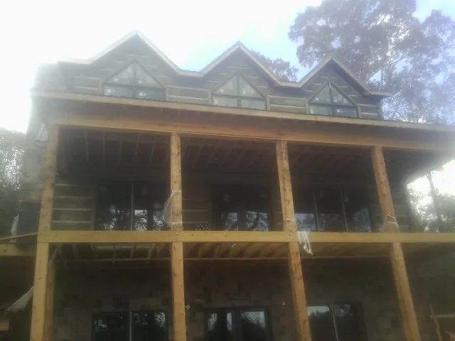 Dormers and porch framing on a large log home under construction — Roof Coating work by our crew in Rocky Ridge