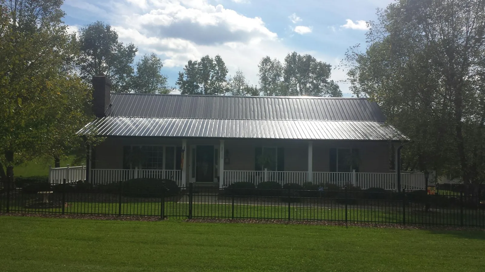 Gray metal roof on a brick ranch with a full width front porch — Gutter Guard Installation work by our crew in Rocky Ridge