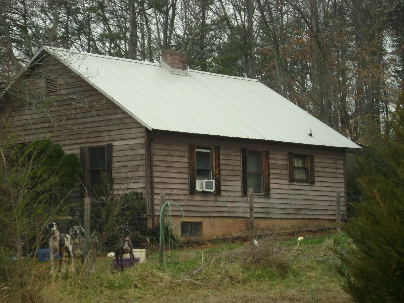 White metal roof on an old wood sided farmhouse, from a Metal Roof Installation job in Rocky Ridge