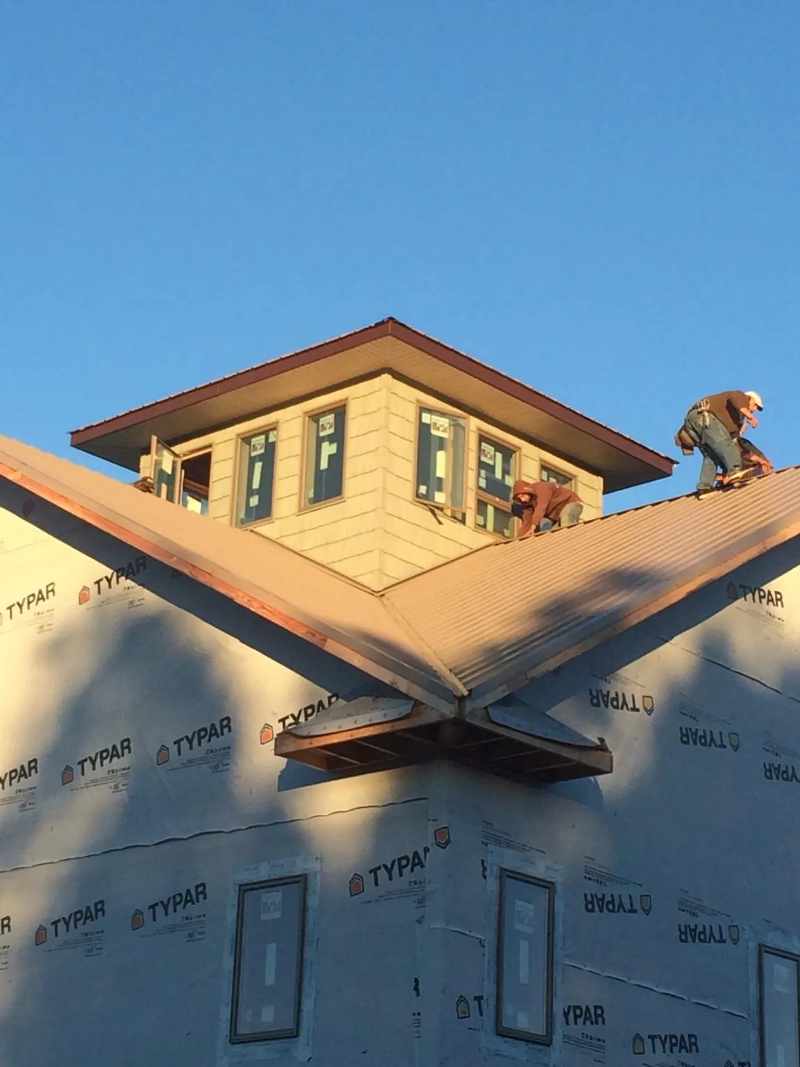 Roofers working around a rooftop cupola on a new metal roof at sunset — Roof Waterproofing in Rocky Ridge by Roofing Brothers